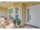 Inviting condo front door with decorative plants and chair seating on the porch at 5211 Mahogany Run Ave # 126, Sarasota, FL 34241