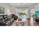 Cozy living room with a leather sofa, ceiling fan, outdoor view, and wood-look flooring, perfect for relaxation at 5211 Mahogany Run Ave # 126, Sarasota, FL 34241