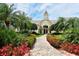 Attractive community clubhouse with manicured gardens, walkway, and lush tropical landscaping, offering a luxurious welcome at 5211 Parisienne Pl # 101B27, Sarasota, FL 34238