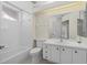 Bright bathroom features a tub, shower, white vanity, and large mirror reflecting the entrance at 6766 Greenview Ln, Englewood, FL 34224