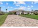 Landscaped home exterior with a brick driveway and lush green lawn under a bright blue sky at 6766 Greenview Ln, Englewood, FL 34224