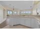 Open kitchen features white cabinets, tile floors, breakfast bar and views of screened-in lanai at 6766 Greenview Ln, Englewood, FL 34224