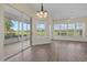 Spacious and bright dining room with wood floors, chandelier, and sliding glass door to lanai at 6766 Greenview Ln, Englewood, FL 34224