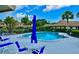 Relaxing community pool area with lounge chairs and umbrellas surrounded by palm trees and greenery at 7183 Wood Creek Dr # 9, Sarasota, FL 34231