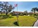 Exterior of a home with a well-manicured lawn, mature trees, and American flag at 7183 Wood Creek Dr # 9, Sarasota, FL 34231