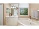Bathroom with large soaking tub, vanity with sink, and a window offering outdoor views at 7351 Meeting St, Bradenton, FL 34201