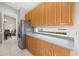 Kitchen featuring stainless steel refrigerator, gray countertops, and warm wood cabinetry at 7351 Meeting St, Bradenton, FL 34201