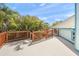 Large deck with wood railing, lush greenery, and views of blue skies at 7677 Saddle Creek Trl, Sarasota, FL 34241