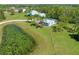 Aerial view of a light blue home and accessory structure, a lily pad pond, and a lush green yard with palm trees at 7677 Saddle Creek Trl, Sarasota, FL 34241