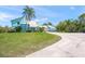 Beautiful light blue two-story home with a metal roof, green lawn, manicured bushes, and a concrete driveway at 7677 Saddle Creek Trl, Sarasota, FL 34241