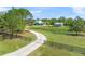 Scenic view of a light blue home with mature trees, a long driveway, a lily pad pond, and a gated fence at 7677 Saddle Creek Trl, Sarasota, FL 34241