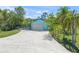 Attached light blue garage with a grey door and a wide concrete driveway surrounded by lush trees at 7677 Saddle Creek Trl, Sarasota, FL 34241