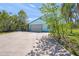 Light blue garage with mature trees and a long concrete driveway at 7677 Saddle Creek Trl, Sarasota, FL 34241