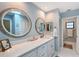 Bathroom featuring double sinks, round mirrors, and white cabinets at 7767 Pine Trace Dr, Sarasota, FL 34243