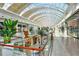 An interior view features a mall with natural light, greenery, and a variety of retail stores at 7767 Pine Trace Dr, Sarasota, FL 34243