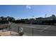 An image of the Palm-Aire Racquet Club tennis courts with players, landscaping and a clear blue sky at 7767 Pine Trace Dr, Sarasota, FL 34243