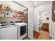 A laundry room with washer, dryer, wire shelving, and an open door to the bathroom at 7959 Limestone Ln # 14-104, Sarasota, FL 34233