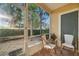 Screened patio with 2 chairs, a table, and green landscaping at 7959 Limestone Ln # 14-104, Sarasota, FL 34233