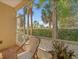 View of trees and sky from screened patio with two chairs and a table at 7959 Limestone Ln # 14-104, Sarasota, FL 34233