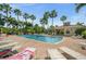Community pool surrounded by lounge chairs, umbrellas, palm trees, and a cabana area at 7959 Limestone Ln # 14-104, Sarasota, FL 34233