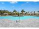 Community pool surrounded by lounge chairs, shaded cabanas, lush landscaping, and swaying palm trees on a sunny day at 8108 Wild Blue Ter, Sarasota, FL 34241