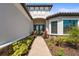 Inviting covered front entrance with double doors, stone accents, and lush landscaping at 8108 Wild Blue Ter, Sarasota, FL 34241