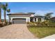 Beautifully landscaped home with a brick driveway and attached two-car garage on a sunny day at 8108 Wild Blue Ter, Sarasota, FL 34241