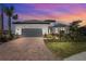 Beautifully landscaped home with a brick driveway and attached two-car garage during a picturesque sunset at 8108 Wild Blue Ter, Sarasota, FL 34241