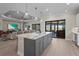 Open kitchen and living area features a gray island with bar seating, stainless steel appliances, and sliding glass doors at 8108 Wild Blue Ter, Sarasota, FL 34241