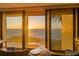 Waterfront living room features floor-to-ceiling windows showcasing the Gulf of Mexico with palm tree at 101 Sunset Dr # 103, Sarasota, FL 34236