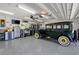 Organized garage with epoxy flooring, cabinets, workbench, and a vintage green automobile at 1208 Angela Maria Rd, Sarasota, FL 34243