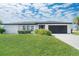 Well-maintained front yard with lush green grass, manicured bushes, and a gray driveway at 1606 Jim Jim Ct, Venice, FL 34293