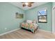 Cozy bedroom with a twin bed, wood floors, tropical ceiling fan, and natural light at 16455 Whale Grey Pl, Bradenton, FL 34211
