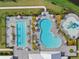 Aerial view of the community's pools and splashpad with lounge seating surrounded by lush landscaping and palm trees at 16455 Whale Grey Pl, Bradenton, FL 34211