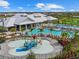 Aerial view of community splash pad with colorful water features and a slide surrounded by palm trees and lounge chairs at 16455 Whale Grey Pl, Bradenton, FL 34211