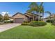 Inviting single-Gathering home featuring manicured lawn, palm trees, and brick-paved driveway at 16719 Ellsworth Ave, Bradenton, FL 34202