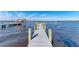 Long wooden dock stretches into deep blue waters with boat lift, and a sunny blue sky backdrop at 2512 Riverside E Dr, Bradenton, FL 34208