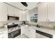 Bright kitchen featuring stainless steel appliances, granite countertops, and white cabinetry at 2512 Riverside E Dr, Bradenton, FL 34208