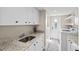 Well-lit laundry room features granite counters, white cabinets and stainless steel sink at 347 Ardenwood Dr, Englewood, FL 34223