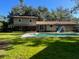 Expansive backyard featuring a pool with a water slide, lush green lawn, and mature trees at 411 El Greco Dr, Brandon, FL 33511