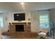 Bright living room with a brick fireplace, modern TV, and a cozy armchair at 411 El Greco Dr, Brandon, FL 33511