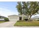 Charming single-story home featuring a well-manicured lawn, mature tree, and attached two-car garage at 4691 Claremont Park Dr, Bradenton, FL 34211