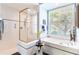 Bright bathroom with a glass-enclosed shower and a soaking tub with window shutters for natural light at 4740 Carrington Cir, Sarasota, FL 34243