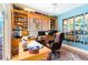 Bright home office featuring custom built-in shelving, a large window, and a comfortable leather chair at 4740 Carrington Cir, Sarasota, FL 34243