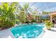 Inviting pool with clear blue water, surrounded by tropical plants, creating a private oasis for relaxation and recreation at 4740 Carrington Cir, Sarasota, FL 34243