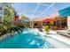 Beautiful pool with sun umbrellas, surrounded by patio furniture perfect for outdoor entertaining, with lush, tropical landscaping at 4740 Carrington Cir, Sarasota, FL 34243
