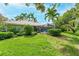 Beautifully landscaped backyard features lush green grass, mature trees, and a screened-in lanai with outdoor seating at 4852 Peregrine Point N Cir, Sarasota, FL 34231