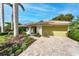 Home exterior with colorful flowering bushes, shade trees, and stone pavers at 4852 Peregrine Point N Cir, Sarasota, FL 34231