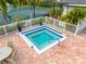 Close-up of a modern hot tub with a white fence, surrounded by brick pavers and tropical plants at 4852 Peregrine Point N Cir, Sarasota, FL 34231