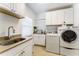 Well-lit laundry room with sink, ample storage, and modern washer and dryer at 4852 Peregrine Point N Cir, Sarasota, FL 34231